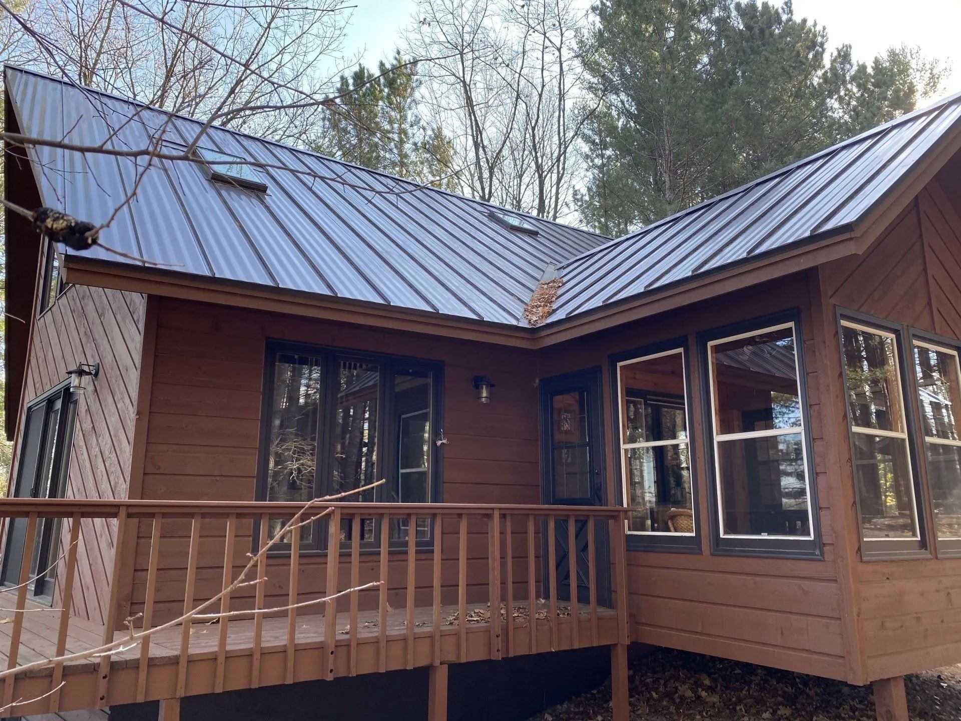 Wooden cabin with a metal roof and front porch surrounded by trees