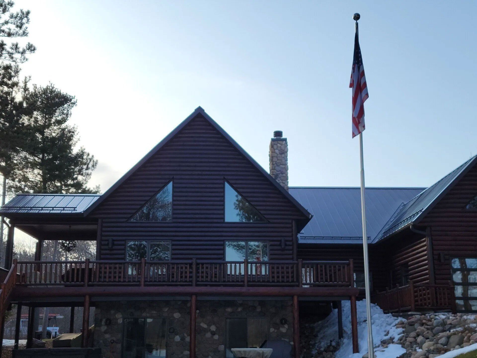 Log cabin-style building with a U.S. flag on a flagpole at sunset