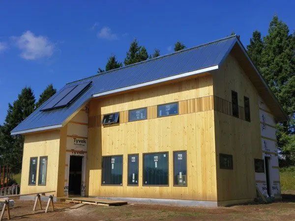 New wooden house with a blue roof and solar panels under a clear sky