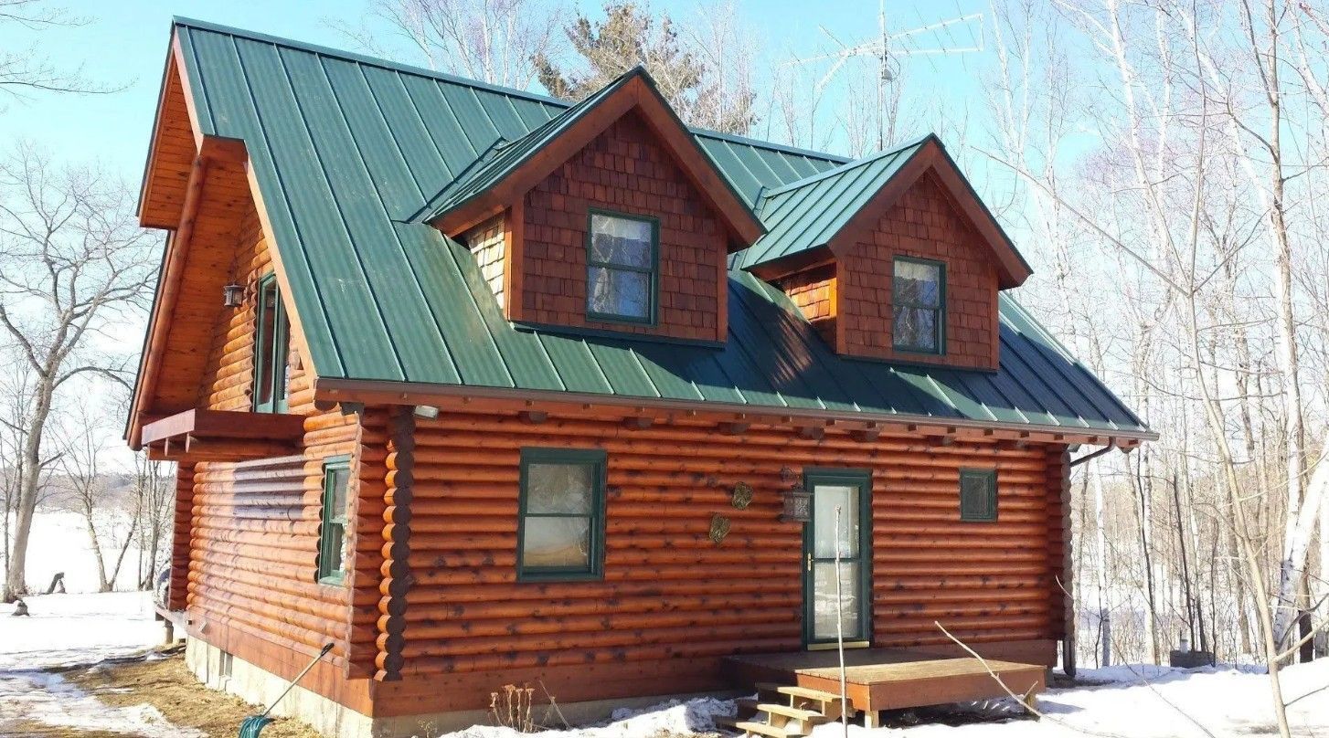 Log cabin with green metal roof in a snowy winter setting