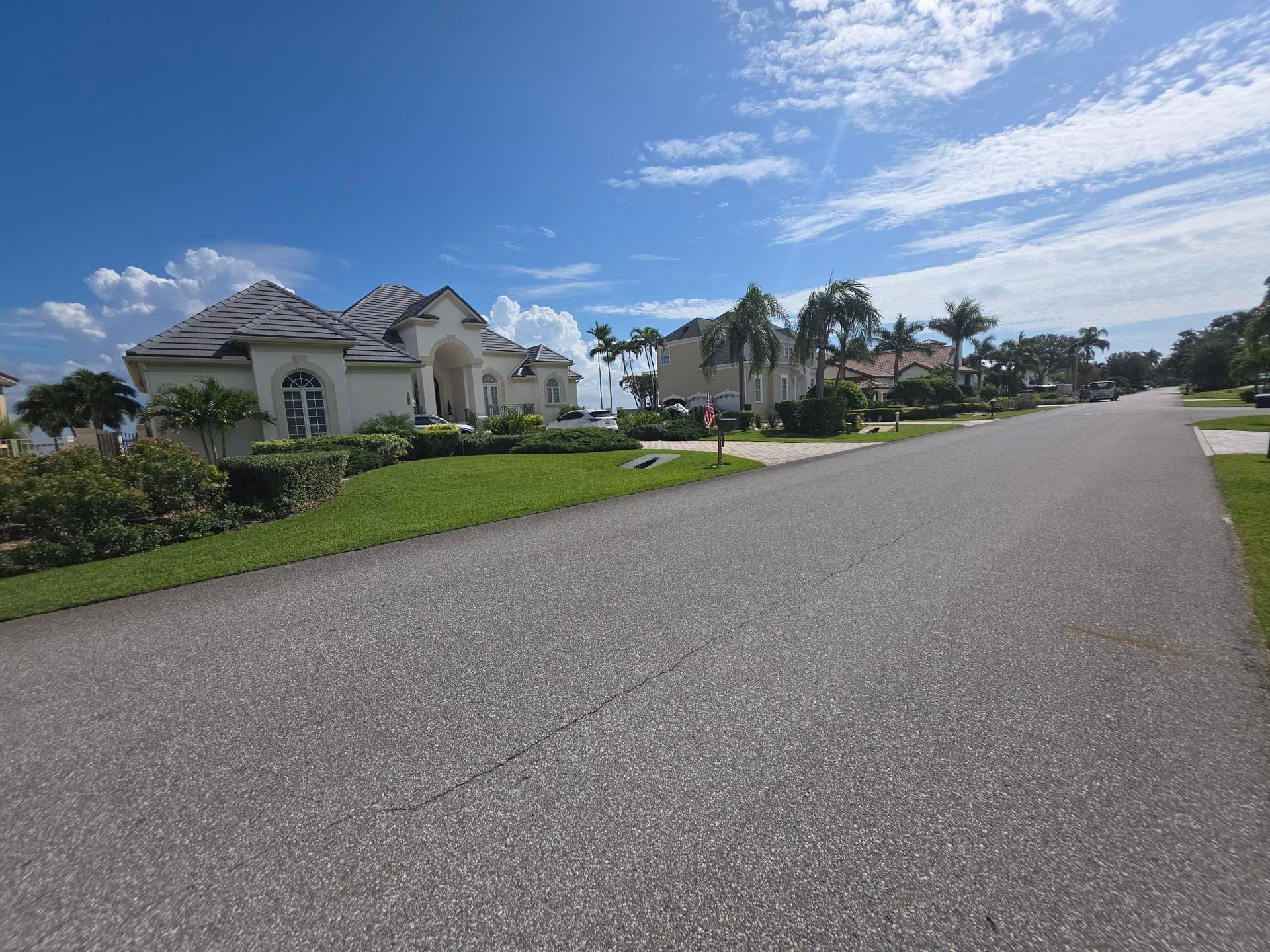 Street lined with large houses under a bright blue sky with wispy clouds.
