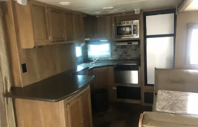 A kitchen in a rv with wooden cabinets and stainless steel appliances.