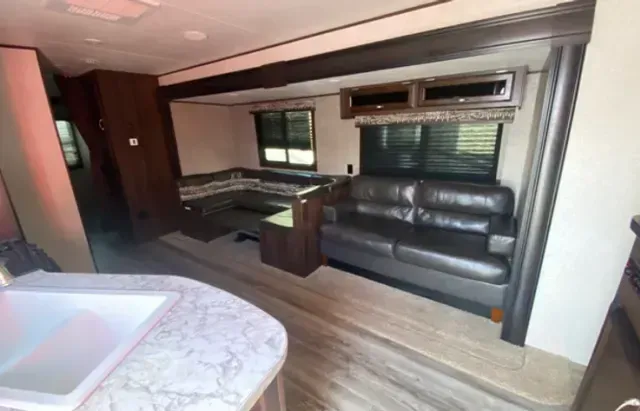 A living room in a trailer with a couch and a sink.