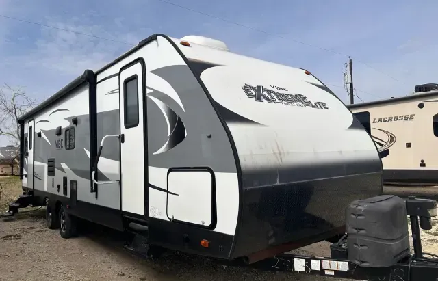 A white and gray trailer is parked on the side of the road.