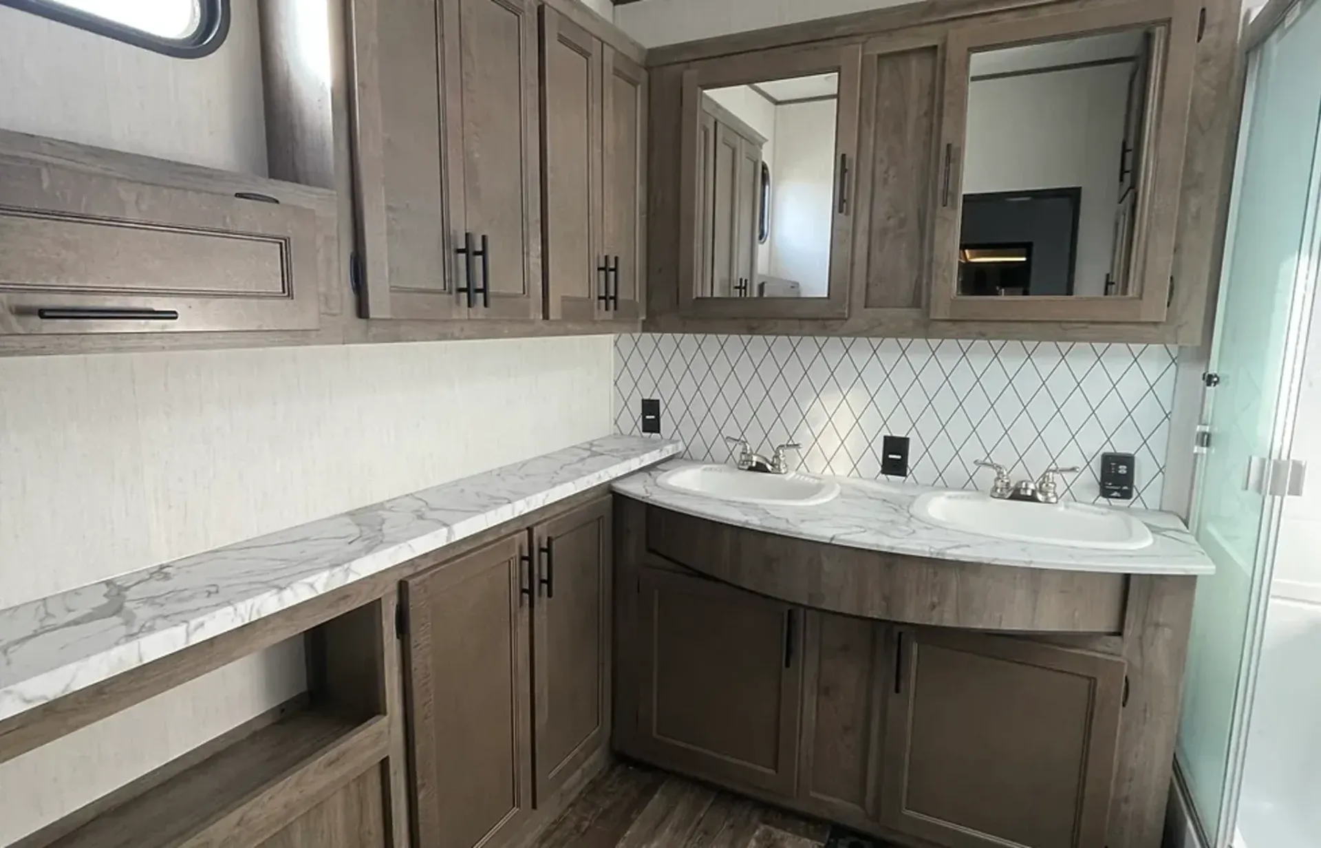 A bathroom in a trailer with two sinks and a mirror.