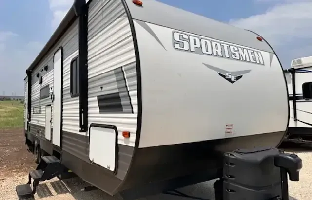 A sportsmen trailer is parked in a dirt lot.