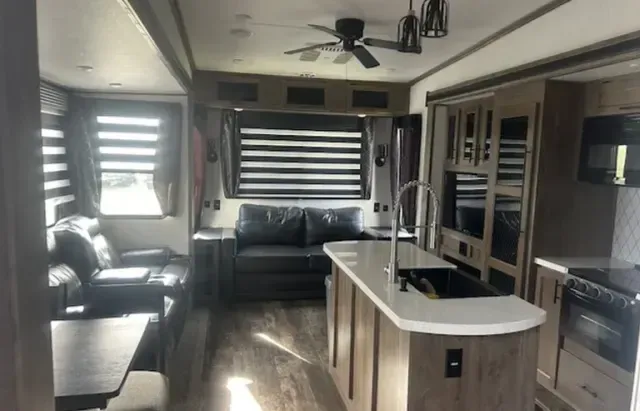 A living room with a couch and a kitchen in a trailer.