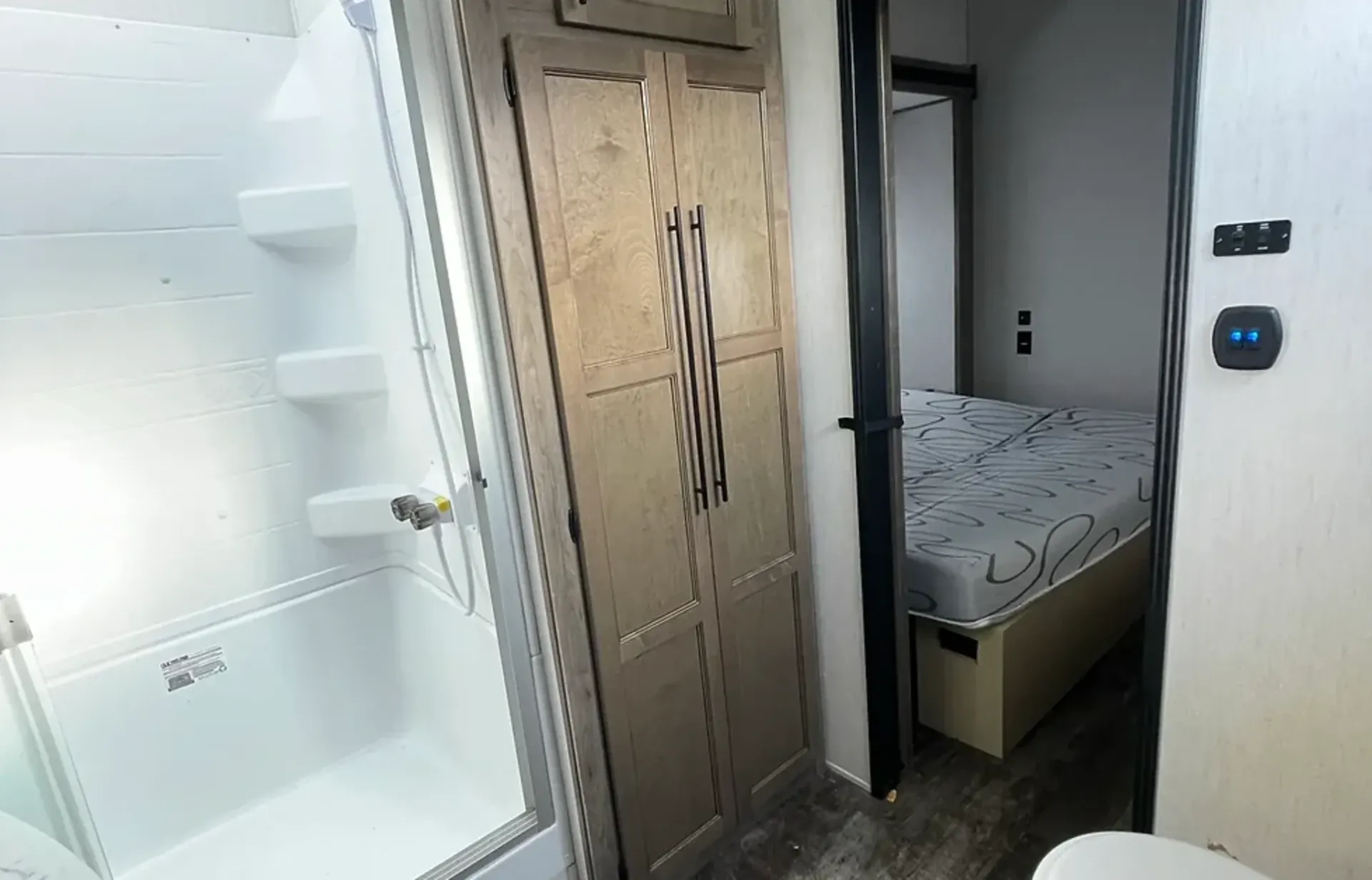 A bathroom with a toilet , shower , and bed.