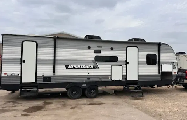 A trailer is parked in a parking lot next to a truck.