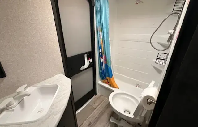 A bathroom with a toilet , sink , shower and bathtub.