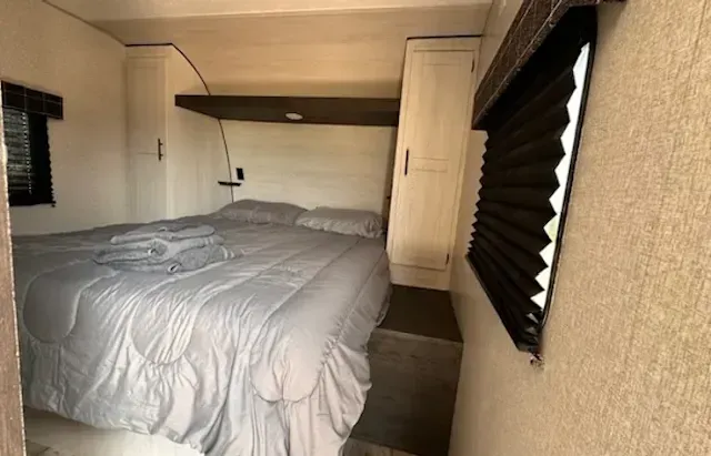 A bedroom in a trailer with a bed and a window.
