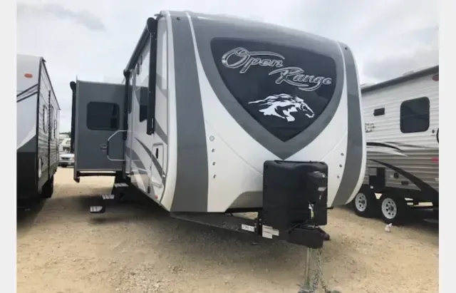 An open range trailer is parked in a dirt lot