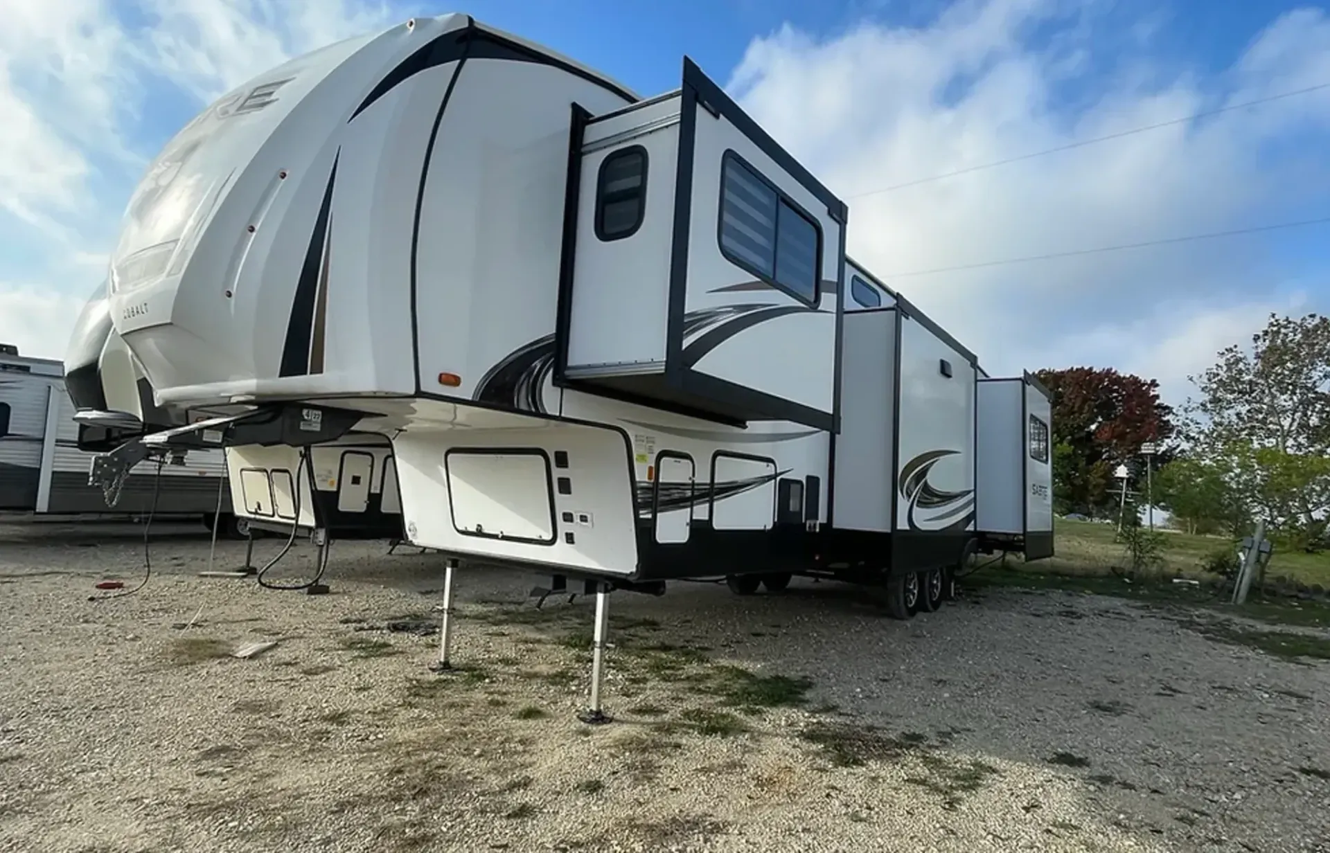 A white trailer is parked in a gravel lot