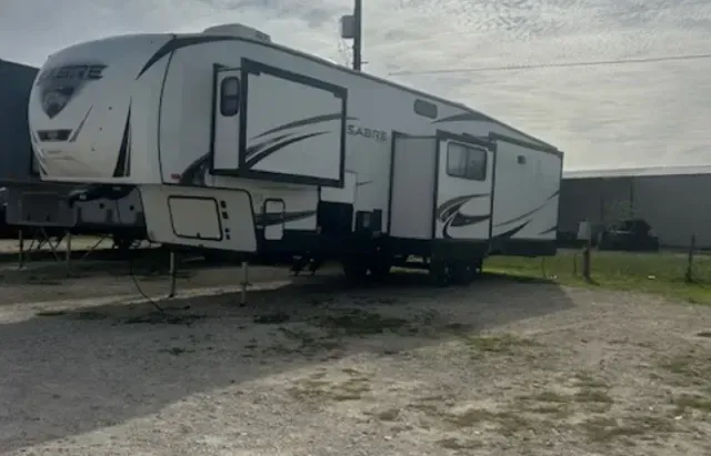 A white rv is parked in a gravel lot.