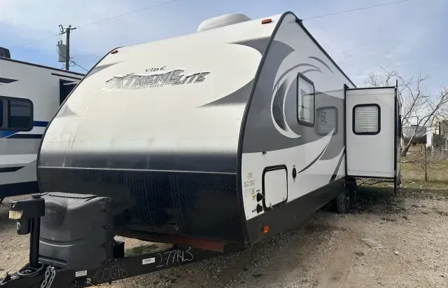 A white and black trailer is parked in a dirt lot.
