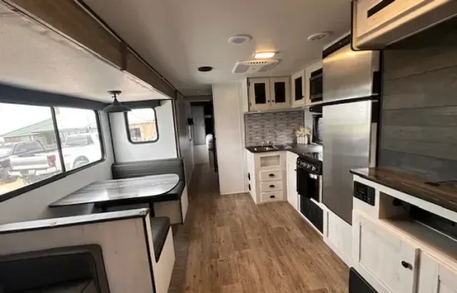 The inside of a rv with a kitchen and dining area.