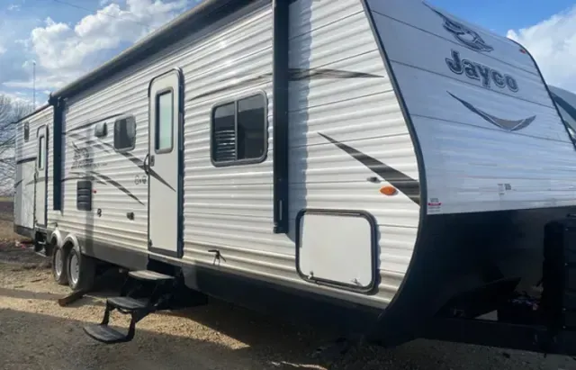 A jayco travel trailer is parked on the side of the road.