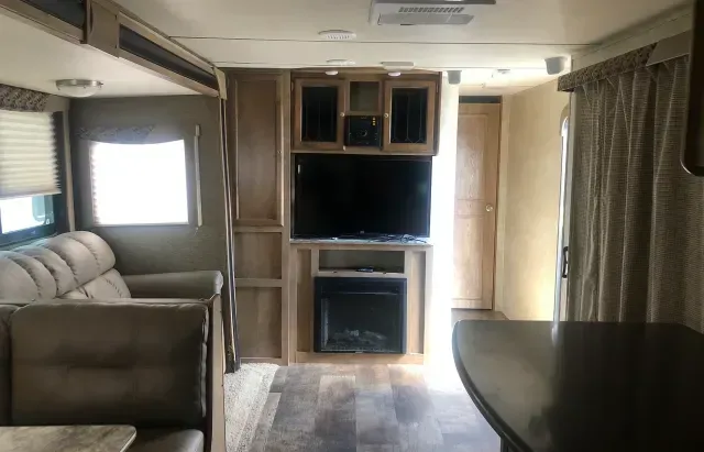 A living room in a rv with a couch , television and fireplace.