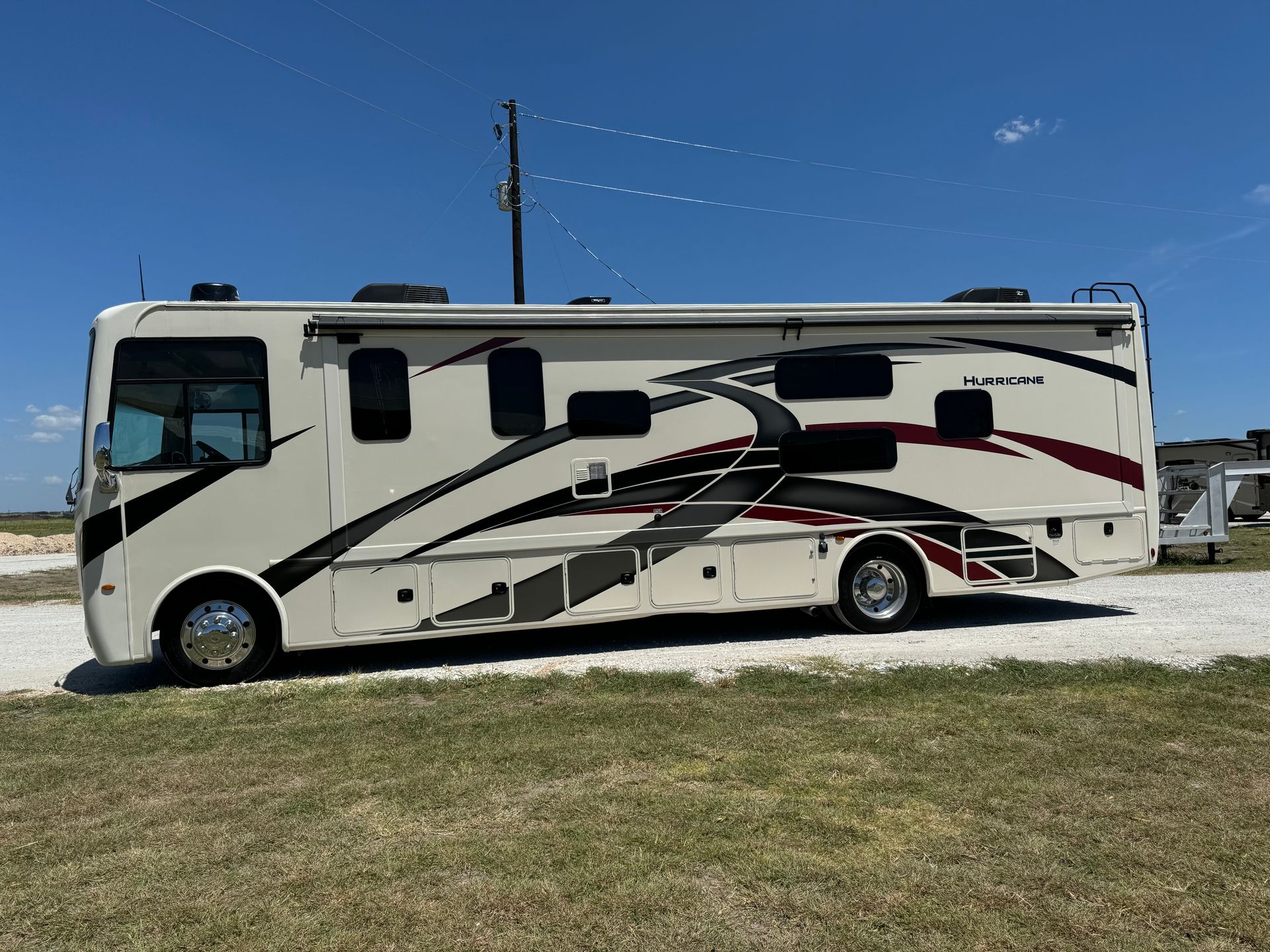 A large white rv is parked in a grassy field.