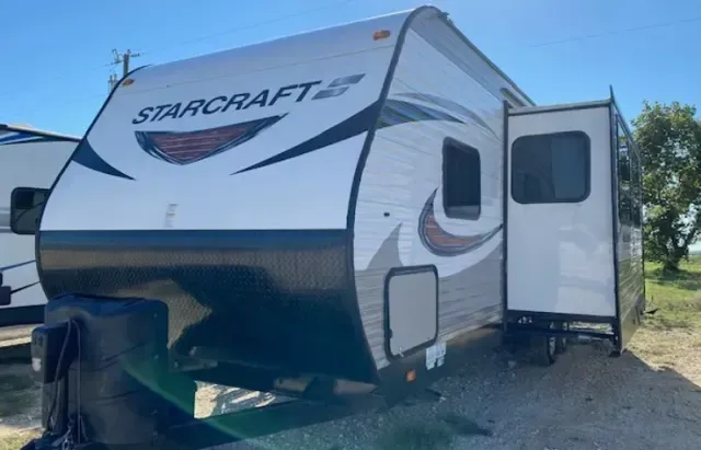 A starcraft trailer is parked in a gravel lot.