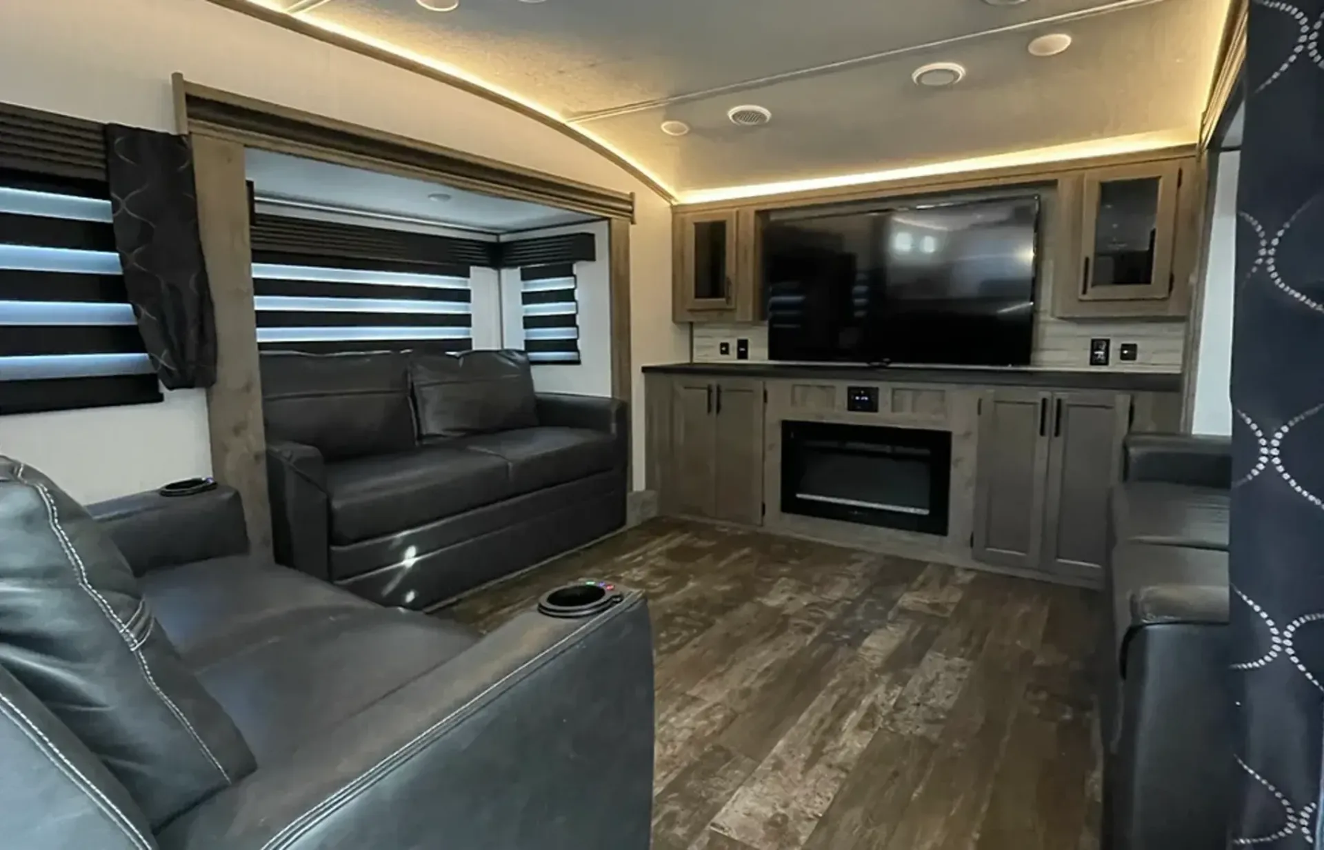 A living room with a couch , chair , television and fireplace.