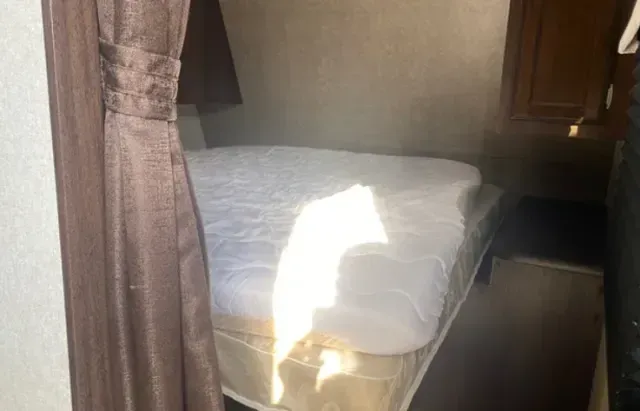 A bed is sitting in a room next to a curtain.