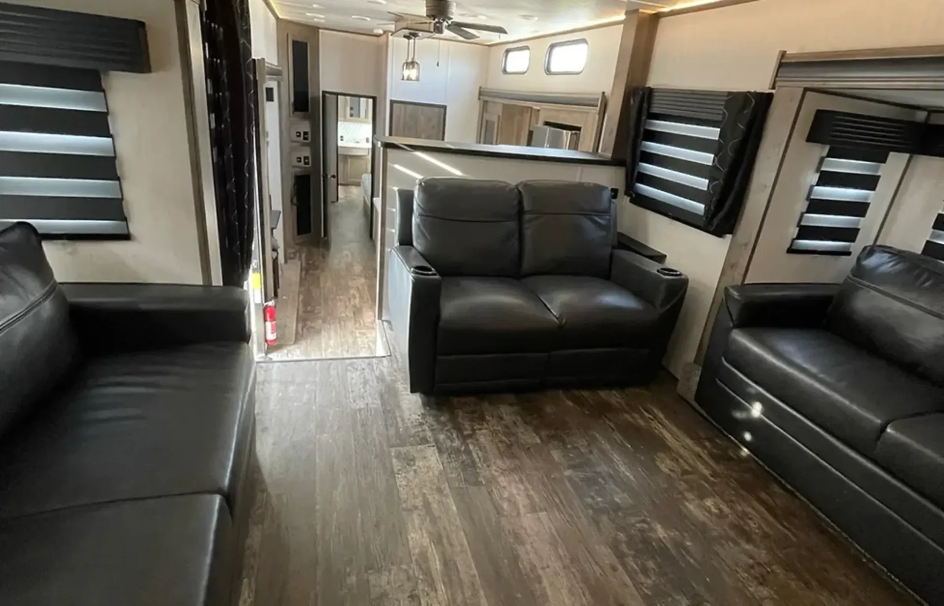 A living room with two black couches and a ceiling fan.