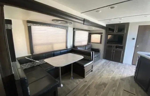 A living room in a rv with a table and couch.