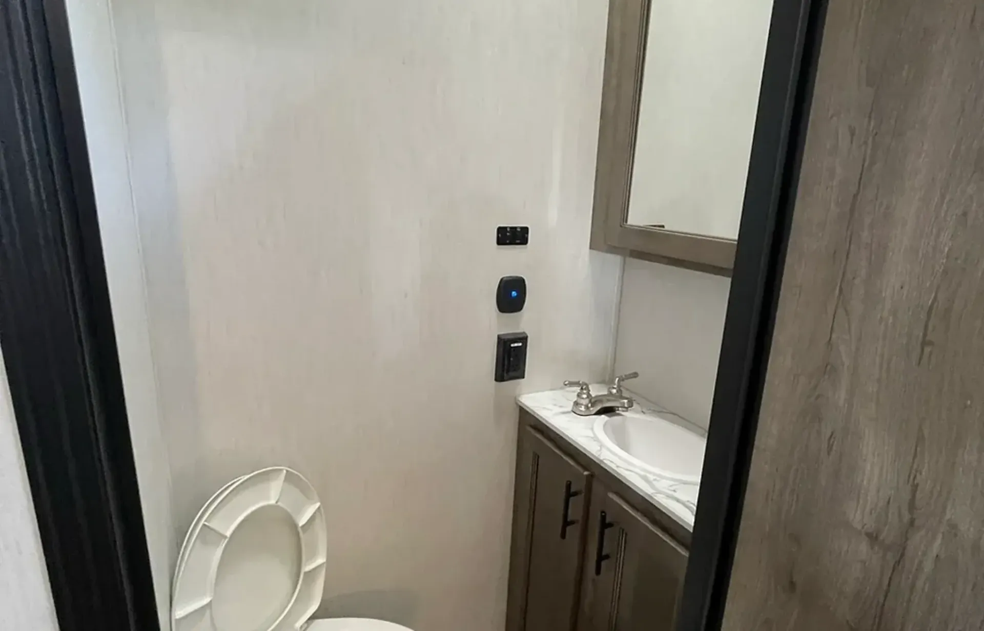 A bathroom with a toilet , sink and mirror.