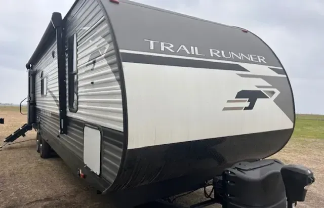 A trail runner trailer is parked in a field.