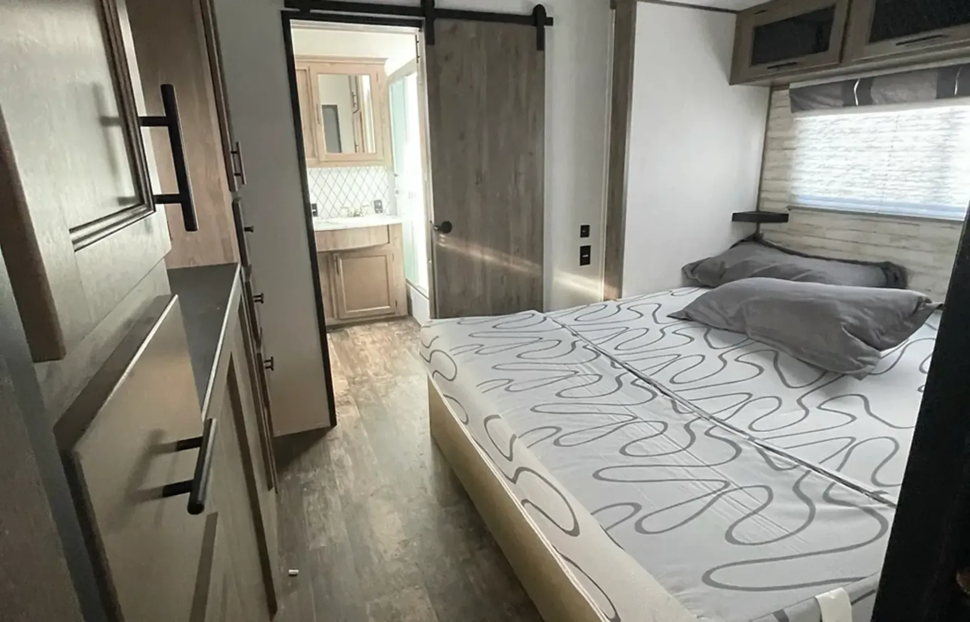 A bedroom with a bed and a sliding barn door.