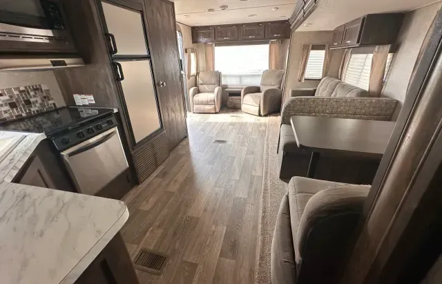 The inside of a rv with a couch , chairs , table and stove.