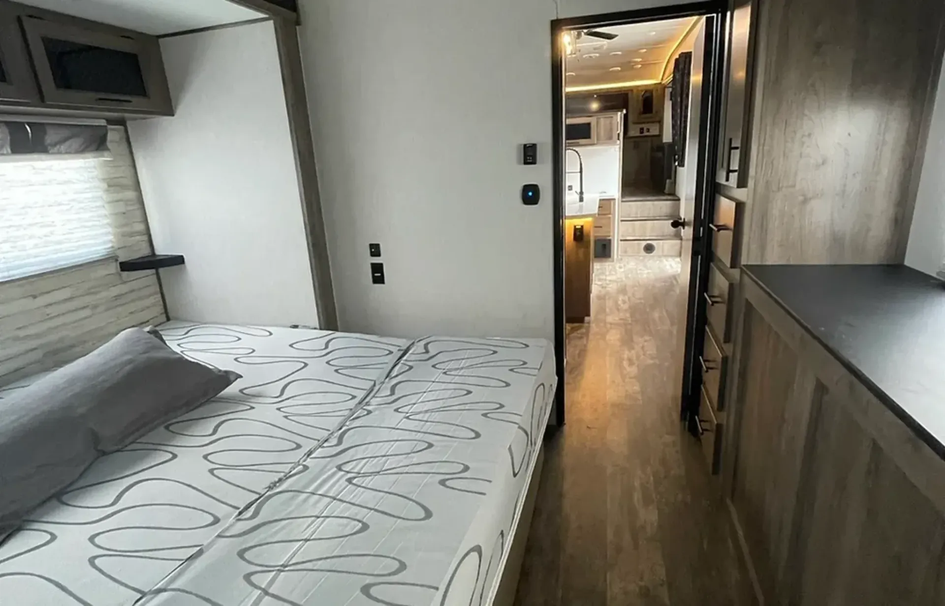 A bedroom in a rv with a bed and a door leading to the kitchen.