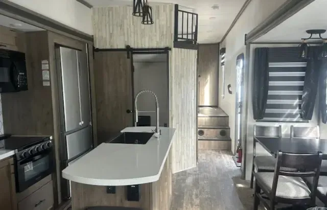 A kitchen with a sink , refrigerator , microwave , stove and table.