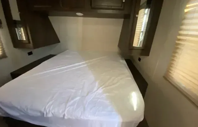 A bedroom with a bed and two windows.