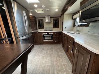 A kitchen with wooden cabinets , stainless steel appliances , and a table.