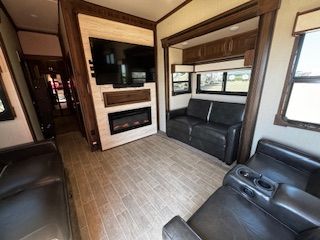 A living room with a couch , chair , television and fireplace.