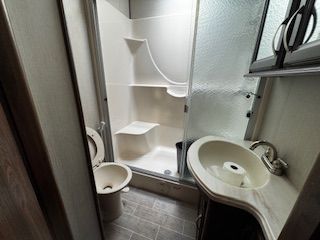 A bathroom with a toilet , sink and shower.