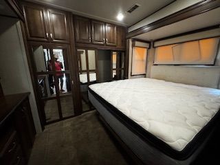 A bedroom with a large bed and lots of cabinets.