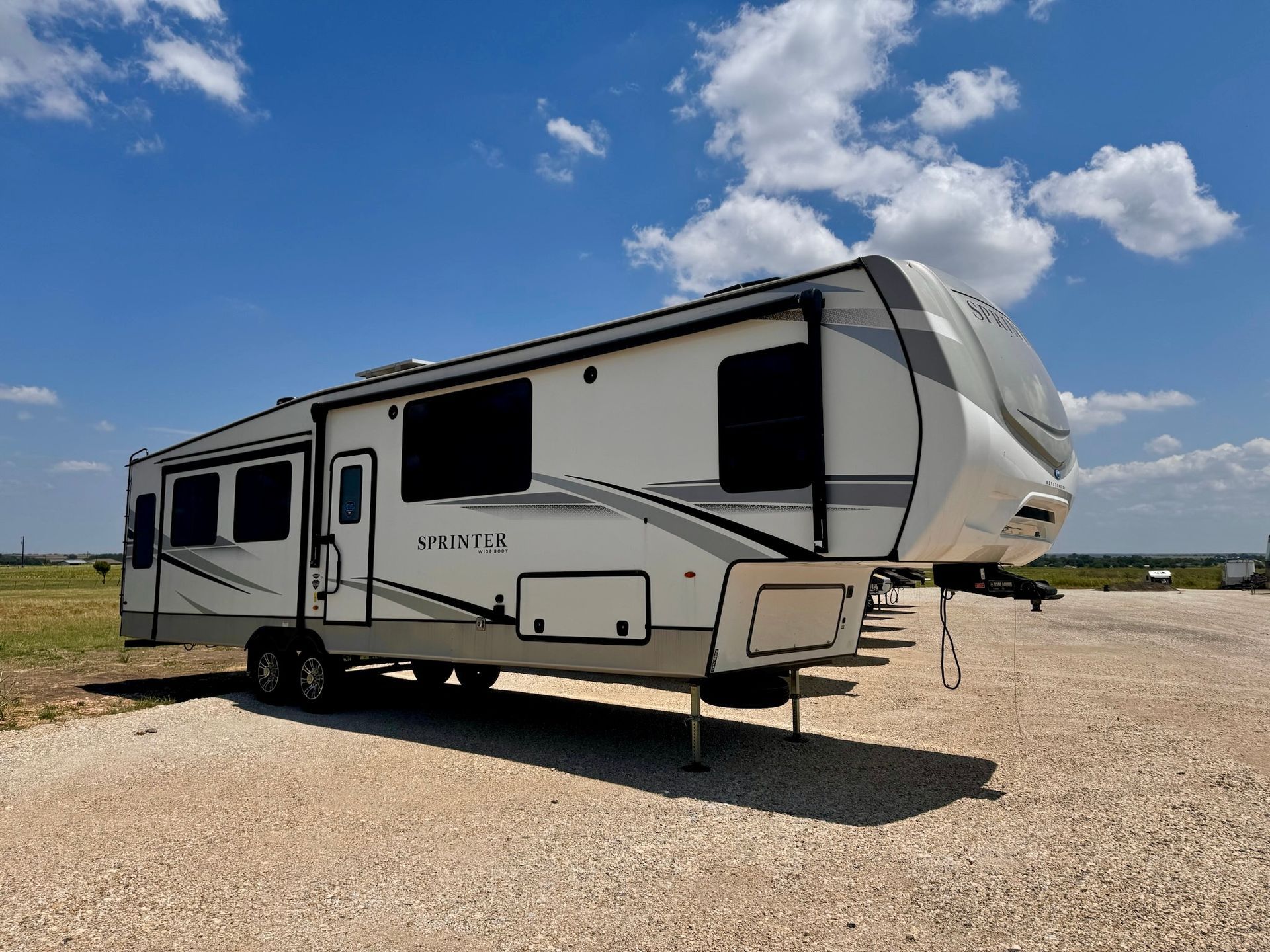 A white rv is parked in a gravel lot.
