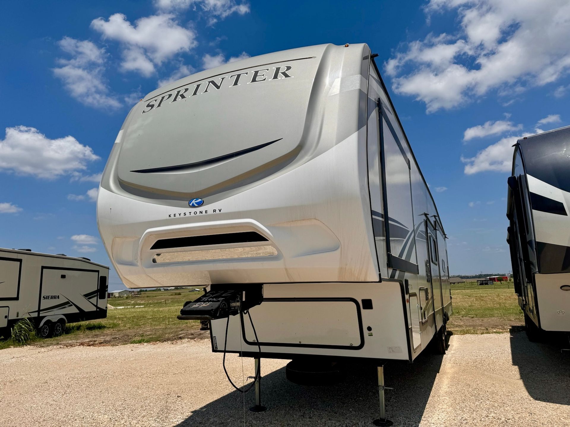 A white rv is parked in a gravel lot.