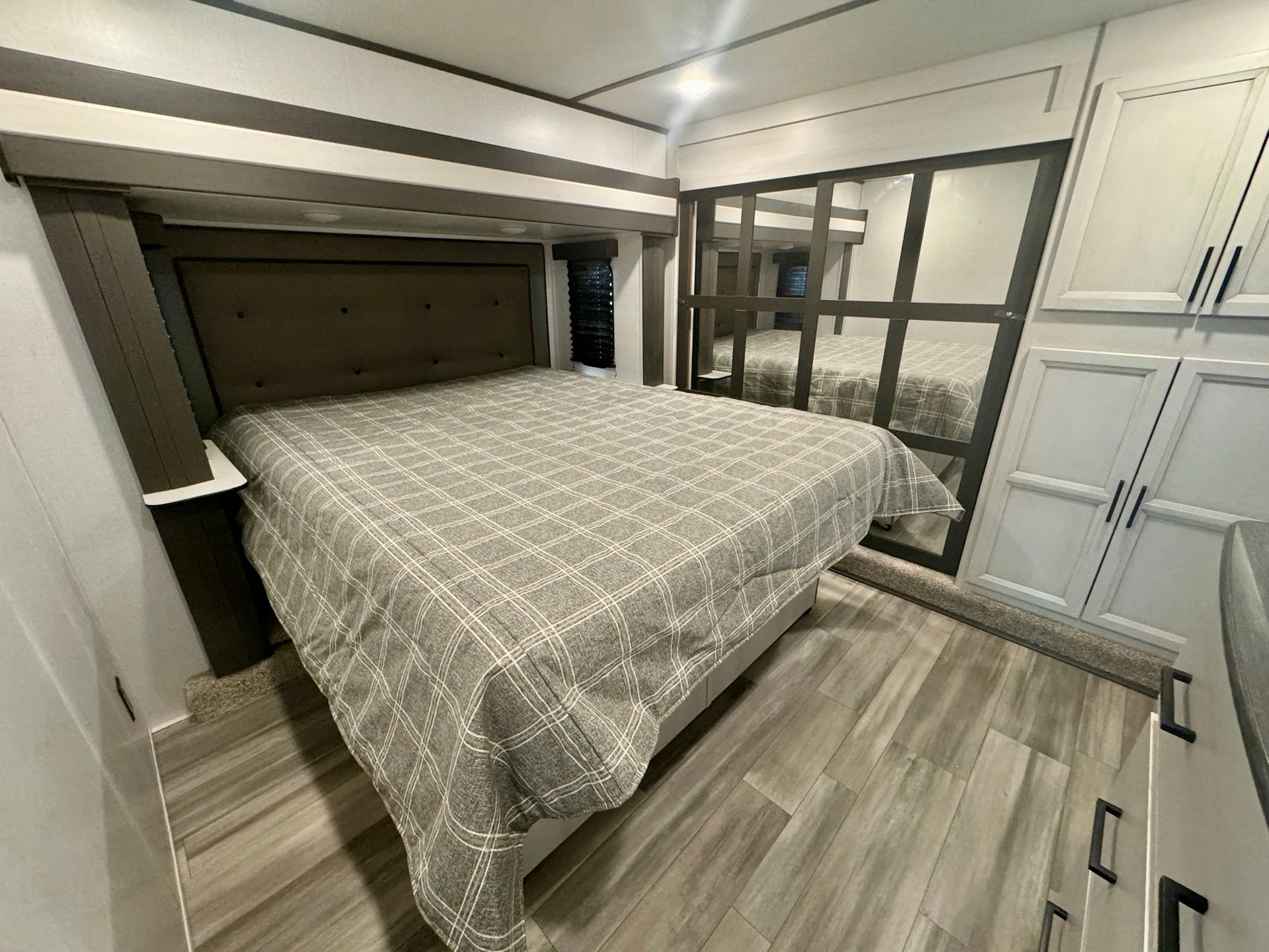 A bedroom with a king size bed and lots of cabinets.
