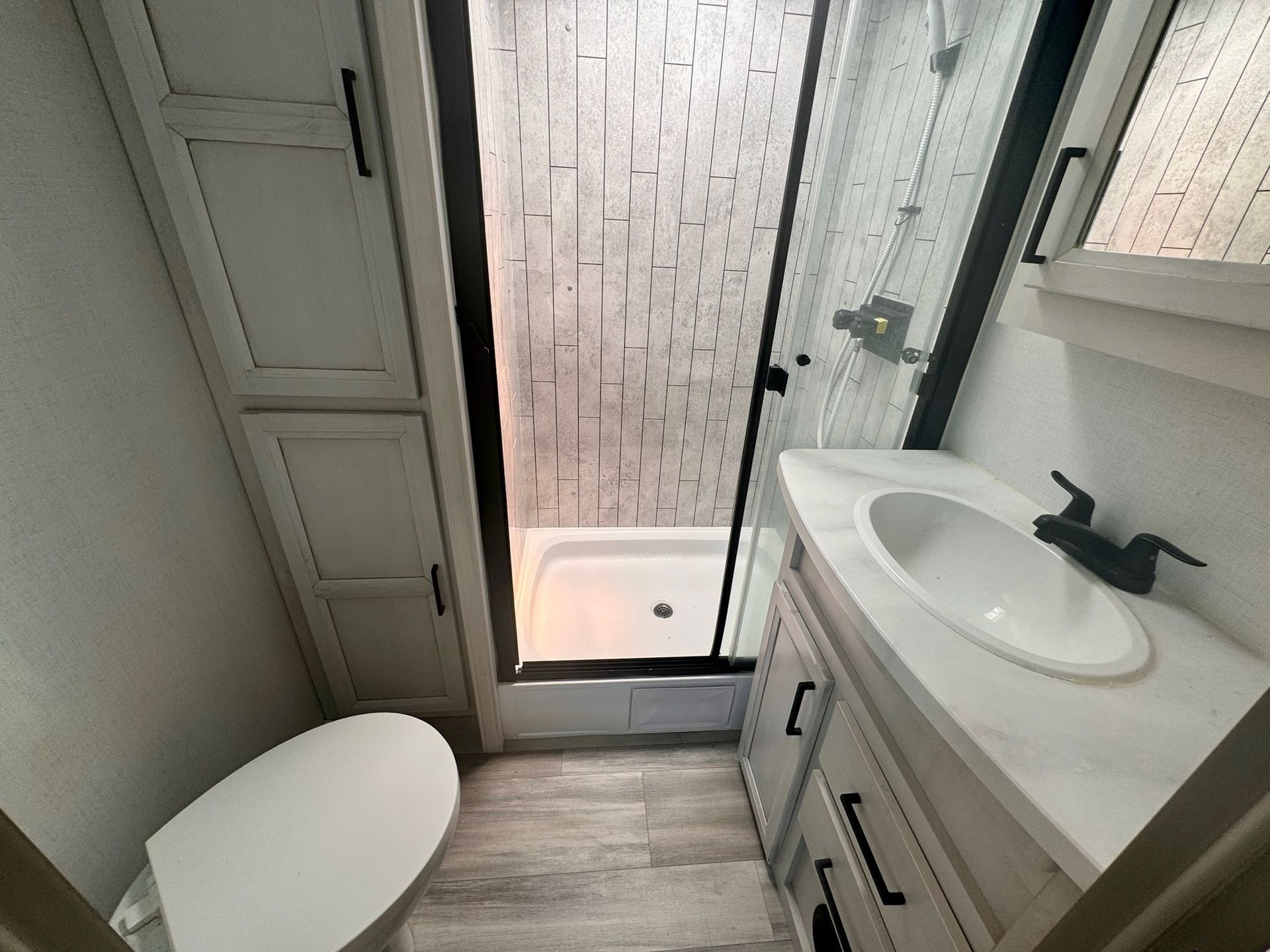 A bathroom with a toilet , sink and shower.