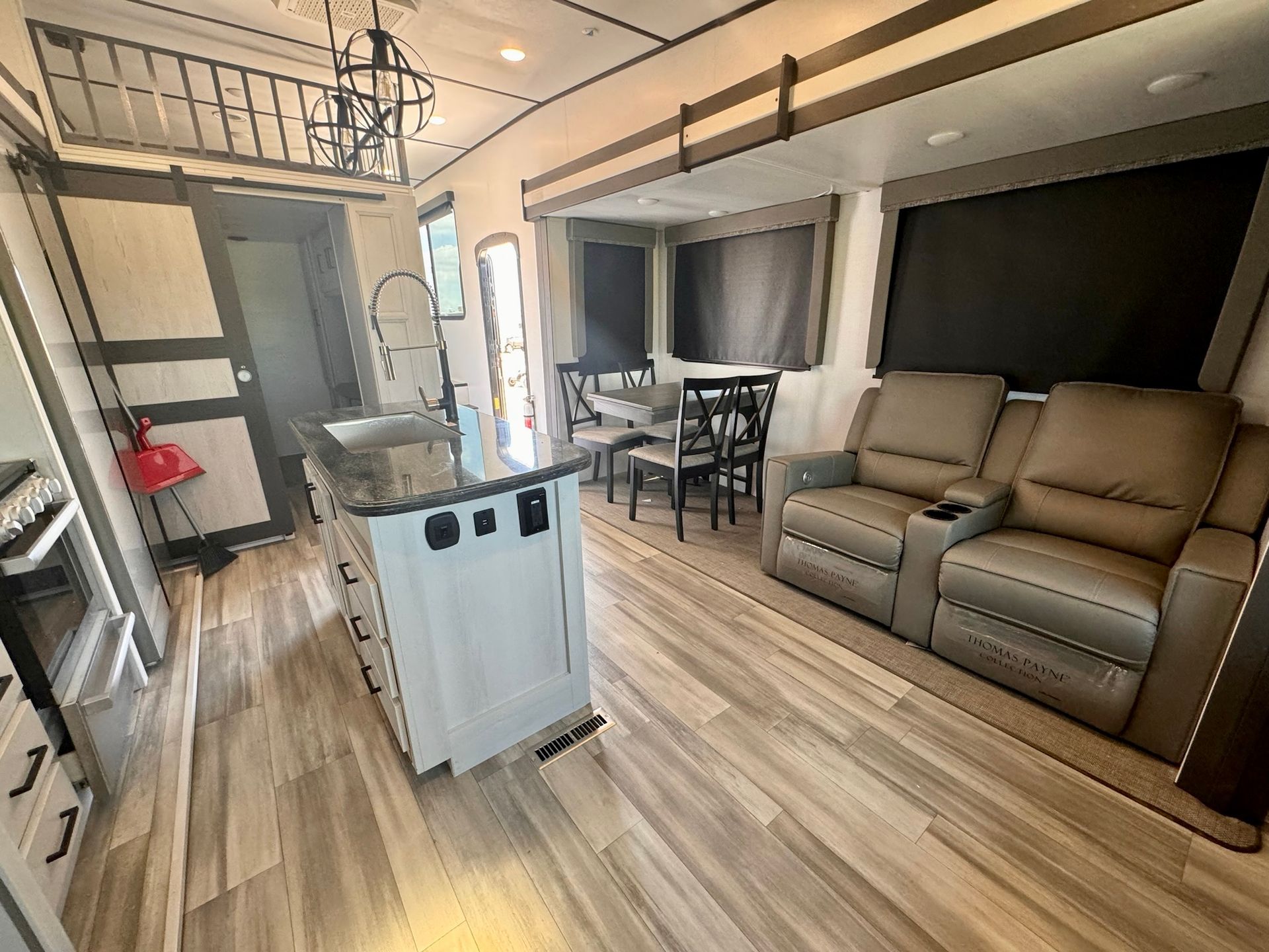 A living room in a mobile home with a couch , chairs , table and sink.