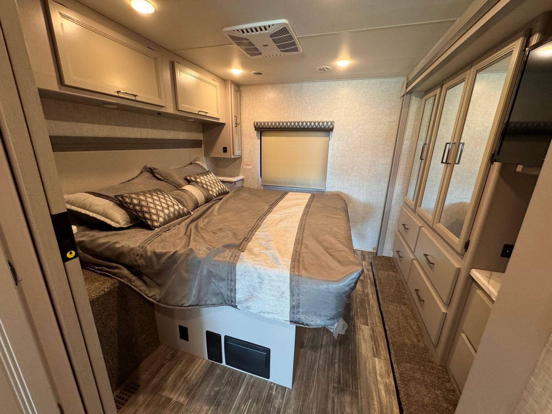 A bedroom in a rv with a large bed and lots of cabinets.