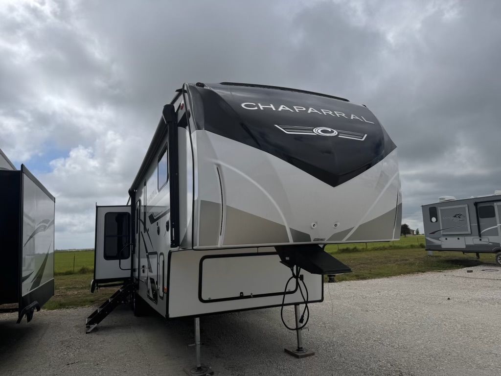 A white and black trailer is parked in a gravel lot.