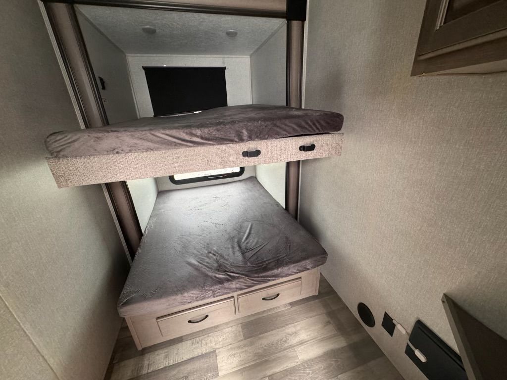 A bunk bed in a rv with drawers underneath it.