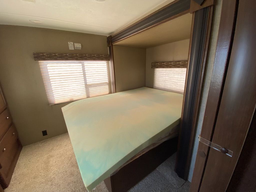 A bedroom with a bed and a window with blinds.