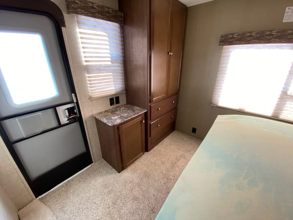 A bedroom with a bed , cabinets , and a screen door.