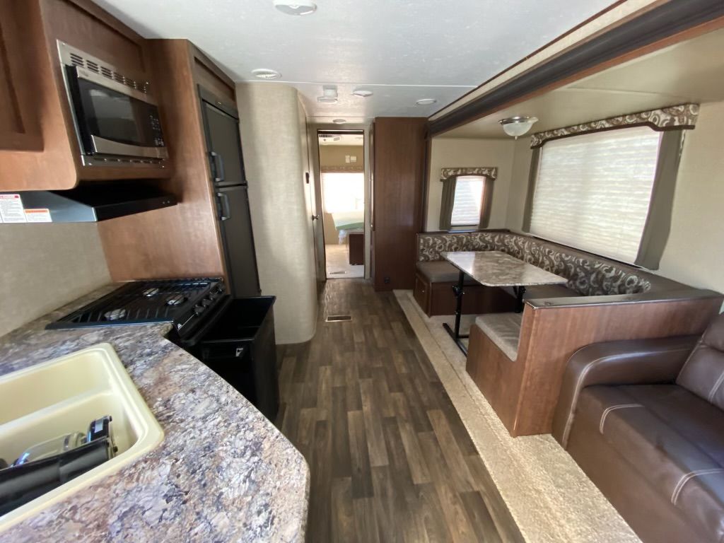 The inside of a rv with a kitchen , dining room , and living room.